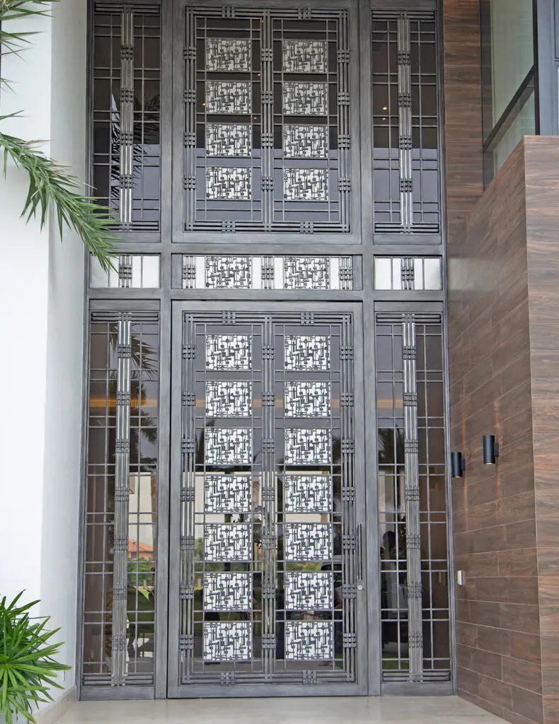 Oversized metal door composed of interlocking and overlapping squares which continuously flow throughout the front entrance